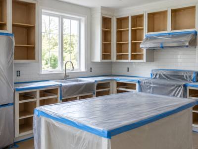 A kitchen masked off with plastic sheeting and tape with the doors removed by Barrie Cabinet Painting.
